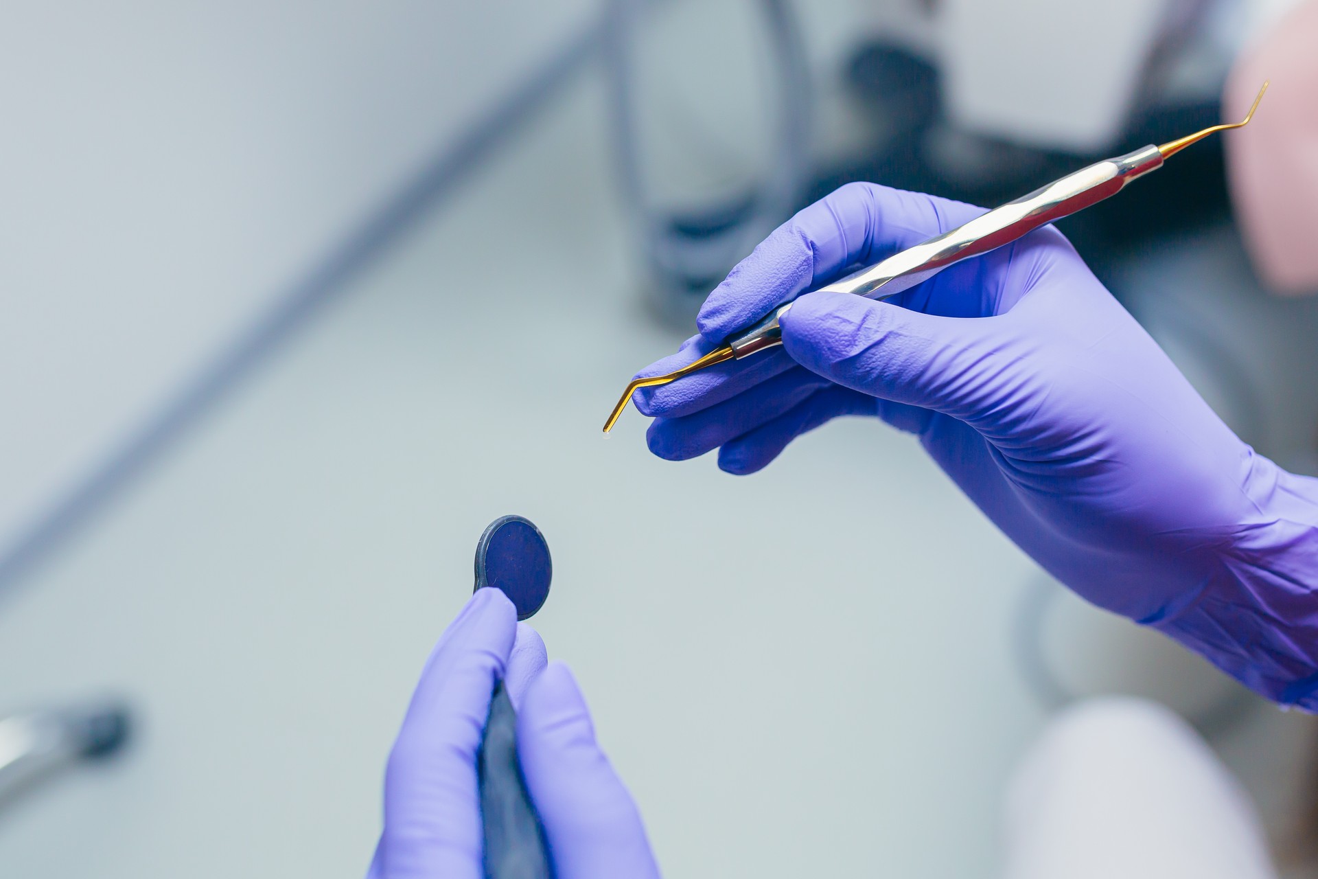 Close up photo doctor's hands in blue medical gloves holding medical dental instruments, preparing for treatment